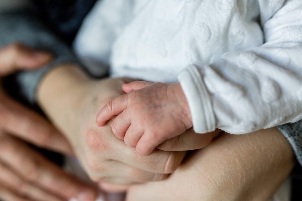 Family hold baby in hands. Baby is in secure embrace with mom and dad.